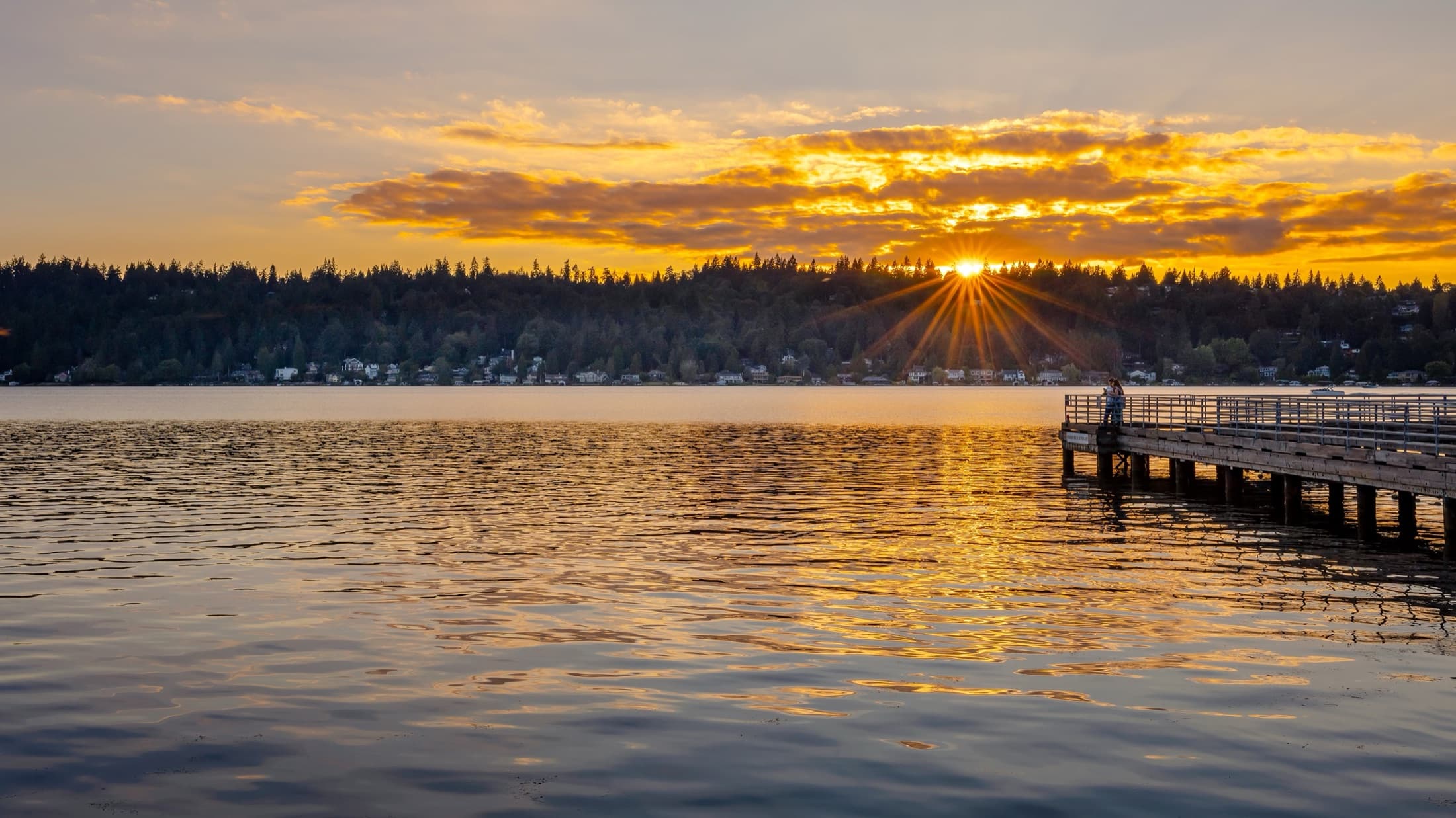 Sunset over the water beside a pier
